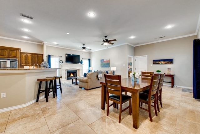 dining area with baseboards, visible vents, ornamental molding, a lit fireplace, and recessed lighting