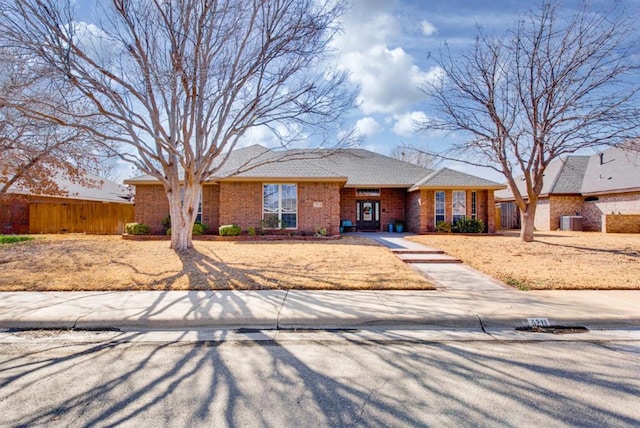 single story home with fence, cooling unit, and brick siding