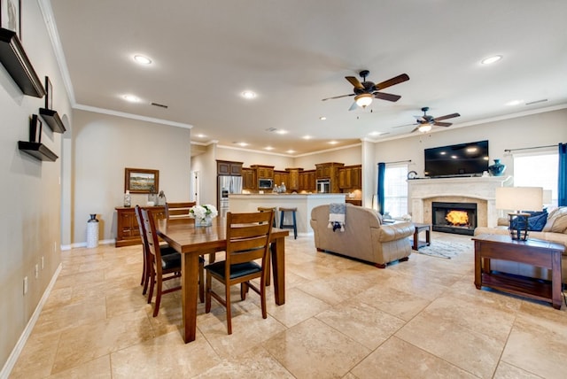 dining space featuring a lit fireplace, crown molding, visible vents, and a wealth of natural light