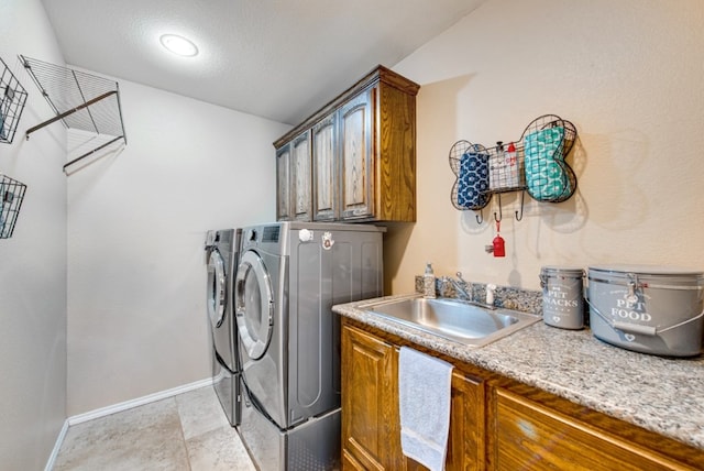 washroom with cabinet space, a sink, baseboards, and separate washer and dryer