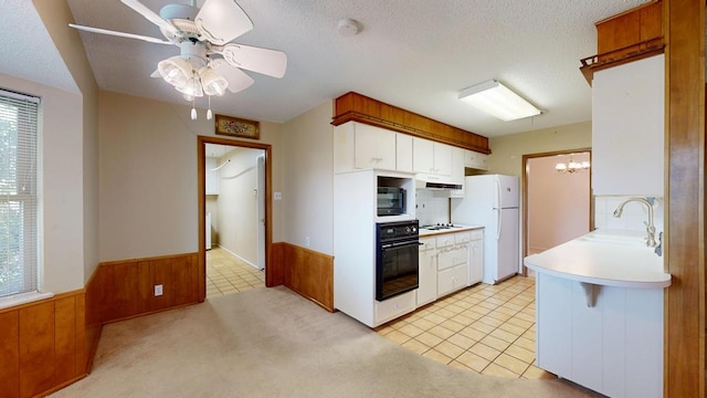 3525 Stanolind Ave, Midland, TX 79707 - kitchen with black appliances, a wainscoted wall, light countertops, wooden walls, and ceiling fan