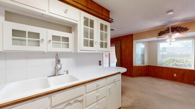 3525 Stanolind Ave, Midland, TX 79707 - kitchen with light countertops, wood walls, a textured ceiling, light colored carpet, and glass insert cabinets