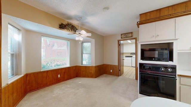 3525 Stanolind Ave, Midland, TX 79707 - kitchen with black appliances, a wainscoted wall, wooden walls, ceiling fan, and white cabinets