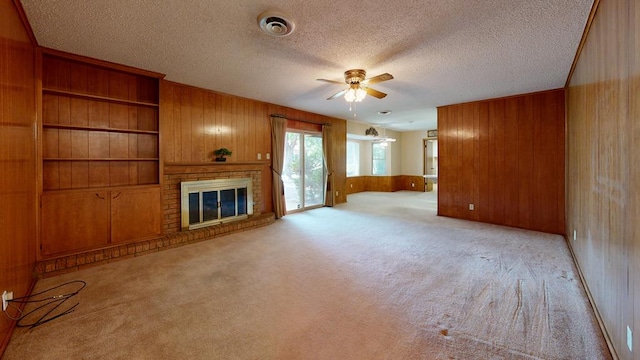 3525 Stanolind Ave, Midland, TX 79707 - unfurnished living room featuring wood walls, ceiling fan, light carpet, a brick fireplace, and a textured ceiling