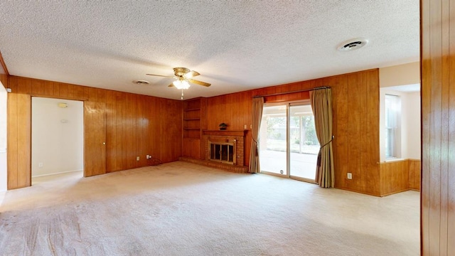3525 Stanolind Ave, Midland, TX 79707 - unfurnished living room featuring wood walls, a ceiling fan, carpet floors, a fireplace, and a textured ceiling