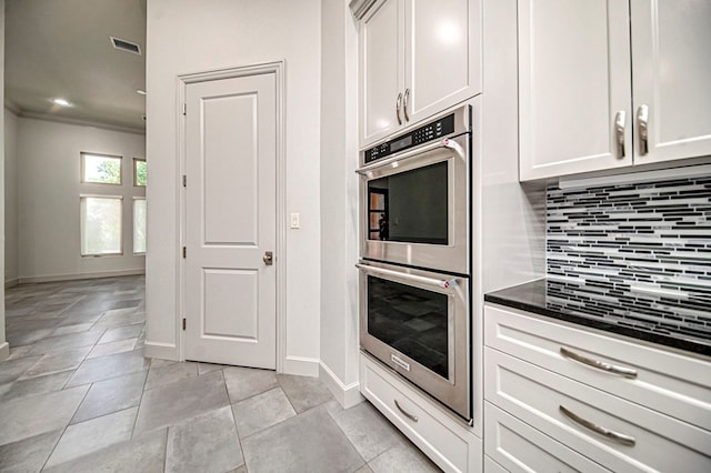 kitchen with tasteful backsplash, white cabinetry, light tile patterned flooring, and double oven