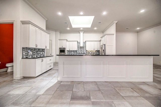 kitchen featuring appliances with stainless steel finishes, a skylight, white cabinetry, and tasteful backsplash