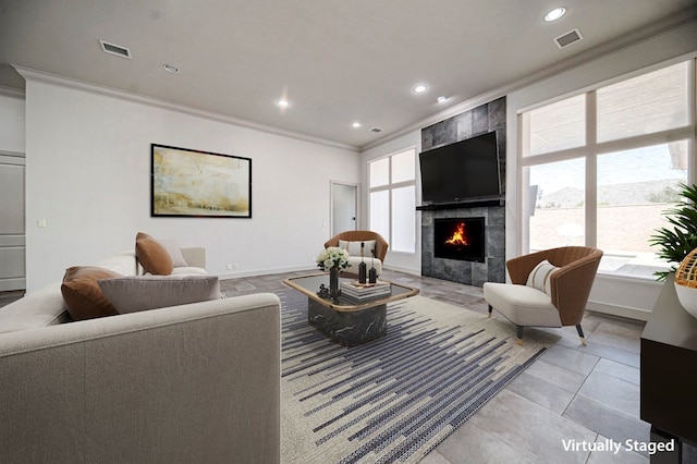 living room with light tile patterned floors, crown molding, and a tile fireplace