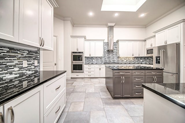 kitchen with backsplash, wall chimney exhaust hood, dark stone countertops, white cabinetry, and stainless steel appliances