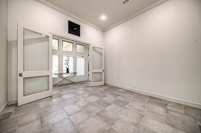 empty room featuring french doors, a towering ceiling, and crown molding