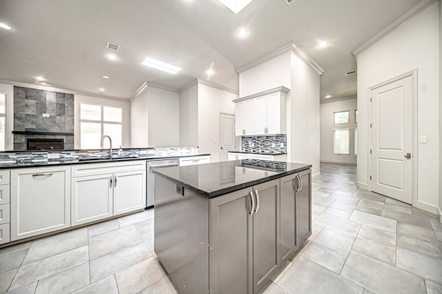 kitchen featuring tasteful backsplash, sink, dark stone countertops, dishwasher, and a kitchen island