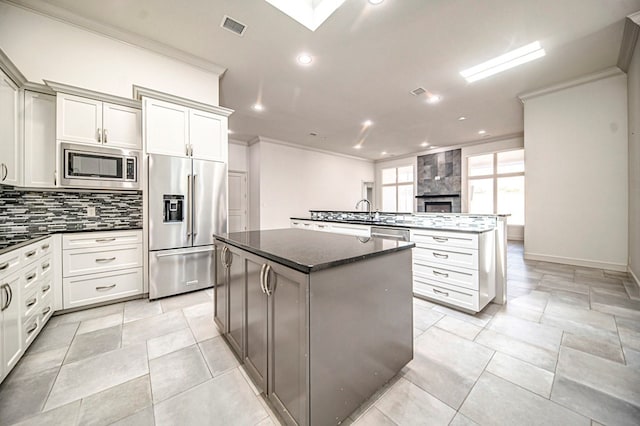 kitchen with tasteful backsplash, crown molding, a kitchen island, and stainless steel appliances