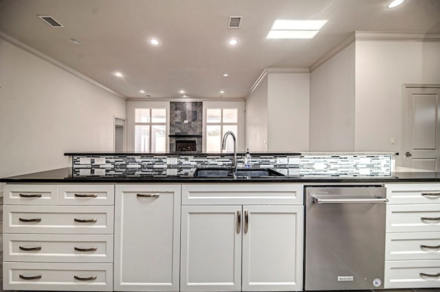 kitchen with backsplash, dishwasher, sink, and white cabinets