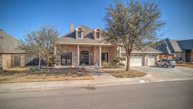 view of front of home with driveway, brick siding, a chimney, and an attached garage