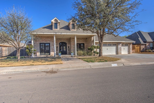 view of front facade featuring concrete driveway, an attached garage, fence, french doors, and brick siding