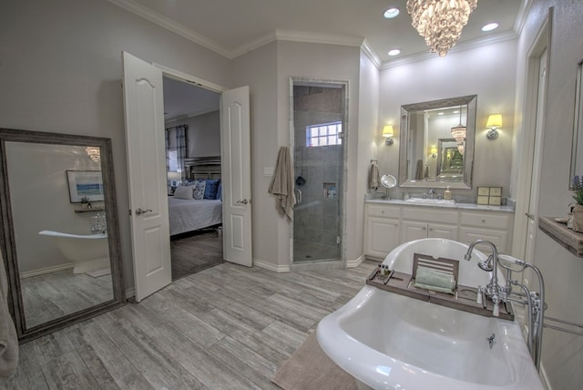 ensuite bathroom with a soaking tub, a stall shower, a sink, ensuite bath, and wood finished floors