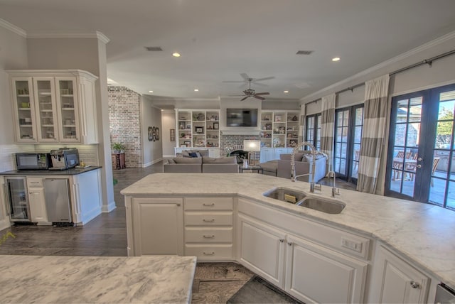 kitchen with a fireplace, visible vents, a sink, and ornamental molding