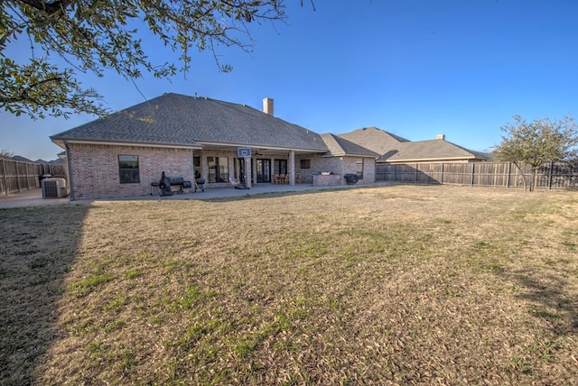 back of house with brick siding, a yard, a patio, central AC, and a fenced backyard