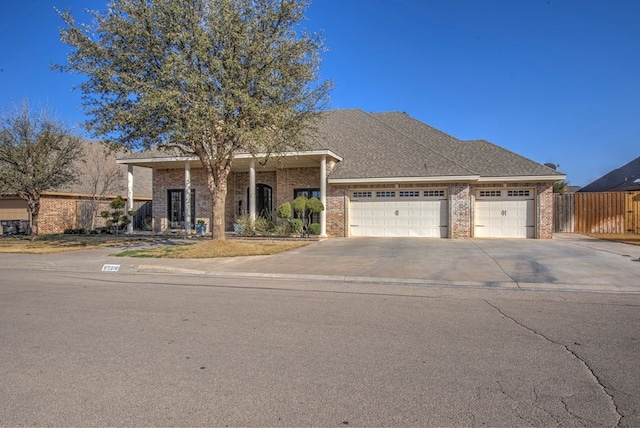 view of front facade featuring brick siding, a shingled roof, an attached garage, fence, and driveway