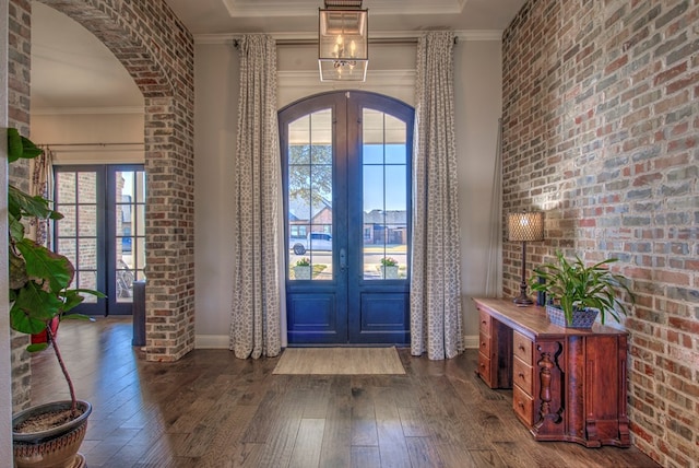 foyer with arched walkways, french doors, brick wall, and hardwood / wood-style flooring