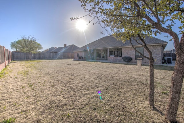 back of house with a yard, a fenced backyard, and brick siding