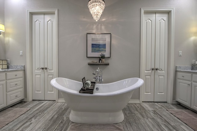 full bathroom featuring a soaking tub, a closet, wood finished floors, and vanity