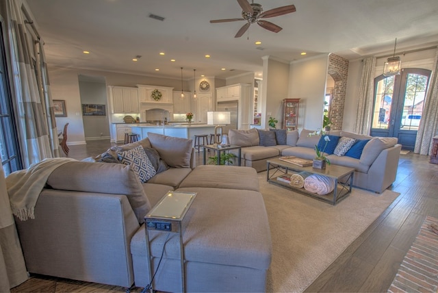 living area featuring french doors, dark wood finished floors, crown molding, recessed lighting, and visible vents