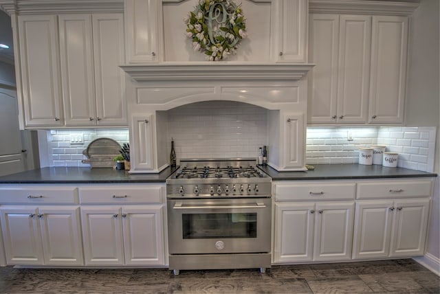 kitchen featuring dark countertops, white cabinetry, and high end stainless steel range