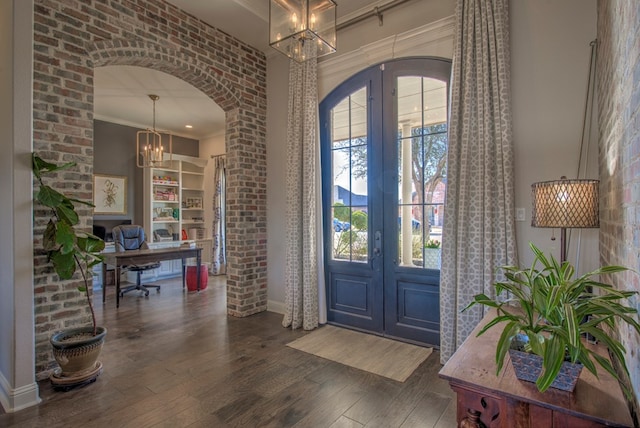 entryway with arched walkways, a notable chandelier, wood finished floors, french doors, and crown molding