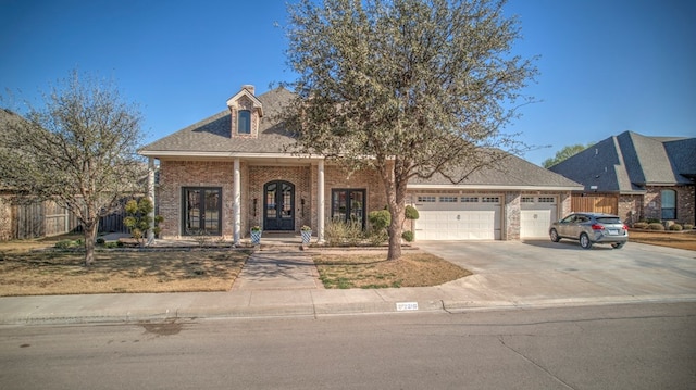 view of front facade featuring a garage, brick siding, fence, driveway, and french doors