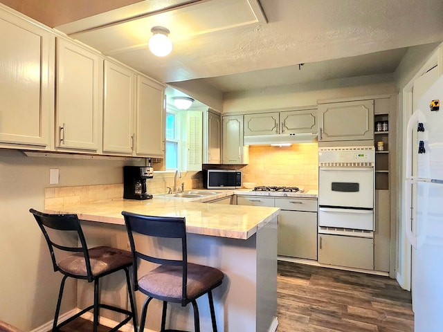 501 W Scharbauer Dr Unit 30, Midland, TX 79705 - kitchen featuring a sink, a warming drawer, a peninsula, white appliances, and dark wood-type flooring