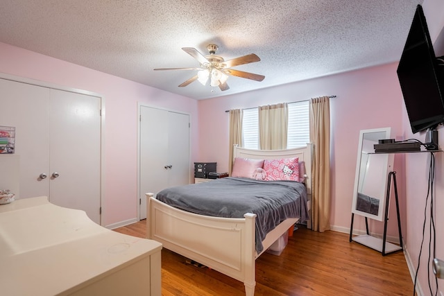 3702 W Michigan Ave, Midland, TX 79703 - bedroom featuring light wood finished floors, a textured ceiling, two closets, and a ceiling fan
