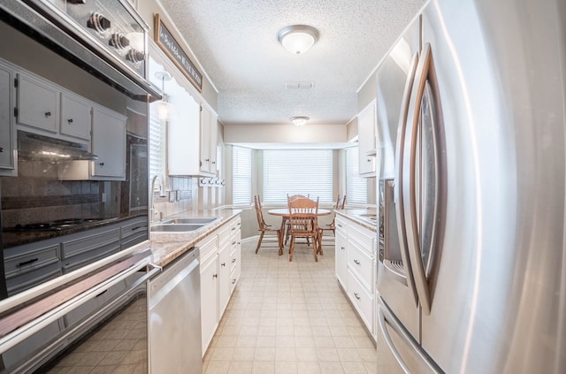 3702 W Michigan Ave, Midland, TX 79703 - kitchen with stainless steel appliances, a textured ceiling, backsplash, light flooring, and gray cabinets