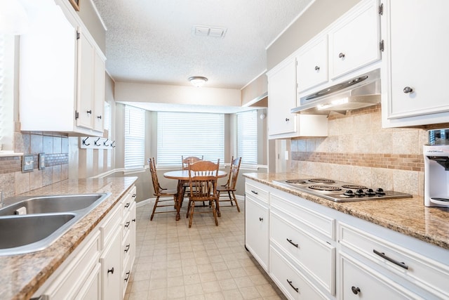 3702 W Michigan Ave, Midland, TX 79703 - kitchen featuring under cabinet range hood, stainless steel stovetop, white cabinetry, a textured ceiling, and light flooring