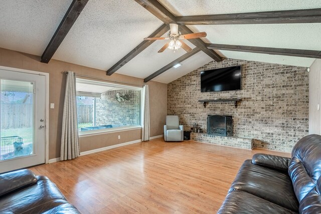 3702 W Michigan Ave, Midland, TX 79703 - living area with a ceiling fan, wood finished floors, a fireplace, a textured ceiling, and brick wall