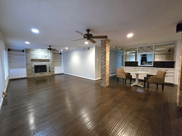 living room with built in shelves, ceiling fan, a textured ceiling, and dark wood-type flooring