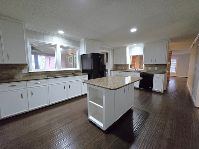 kitchen featuring black appliances, a center island, white cabinets, and sink