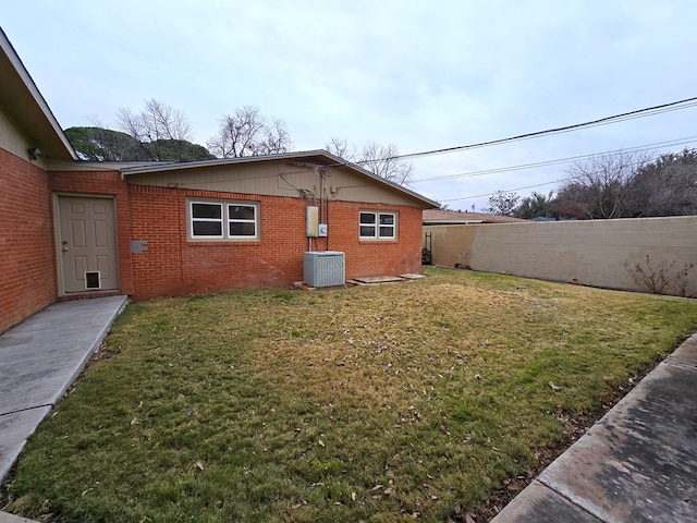 back of property featuring central air condition unit and a lawn