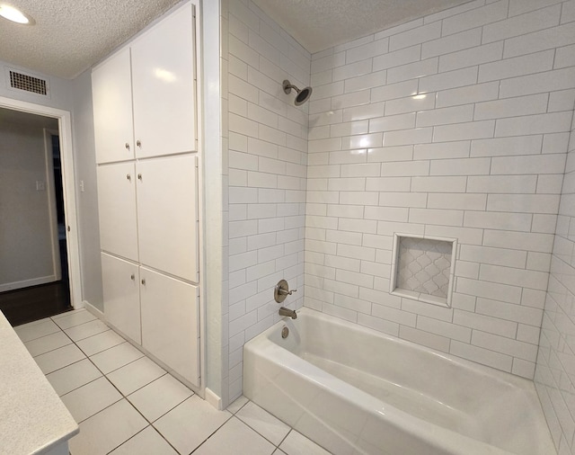 bathroom with tile patterned flooring, vanity, tiled shower / bath combo, and a textured ceiling