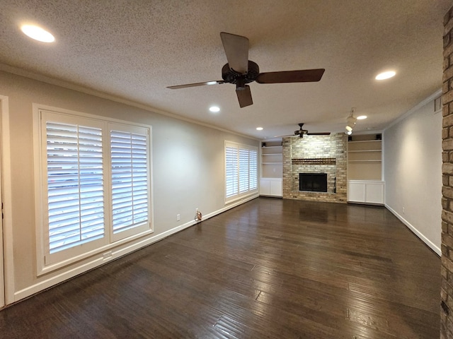 unfurnished living room with dark hardwood / wood-style flooring, ceiling fan, a stone fireplace, and crown molding