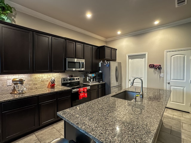 kitchen featuring stainless steel appliances, a kitchen island with sink, sink, and backsplash