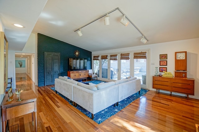 living room featuring hardwood / wood-style flooring, vaulted ceiling, and rail lighting