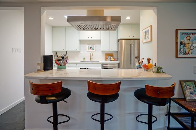 kitchen featuring sink, ventilation hood, high quality fridge, white cabinets, and kitchen peninsula