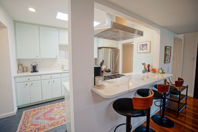 kitchen with white cabinetry, ventilation hood, high end refrigerator, and a kitchen breakfast bar