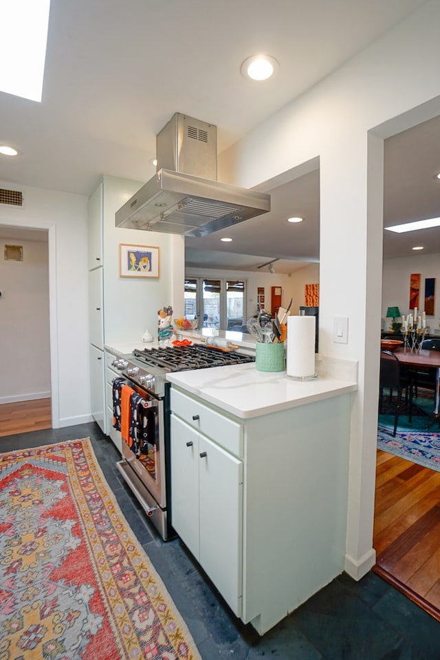 kitchen with white cabinets, dark hardwood / wood-style flooring, island exhaust hood, high end stainless steel range, and kitchen peninsula