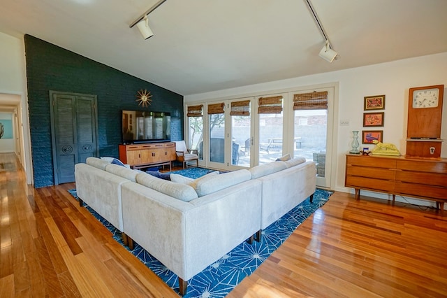 living room featuring vaulted ceiling, wood-type flooring, and track lighting