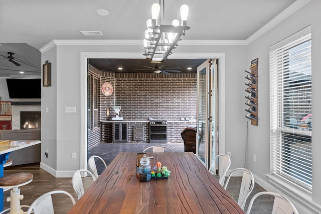 dining area featuring dark hardwood / wood-style flooring, ceiling fan with notable chandelier, and crown molding