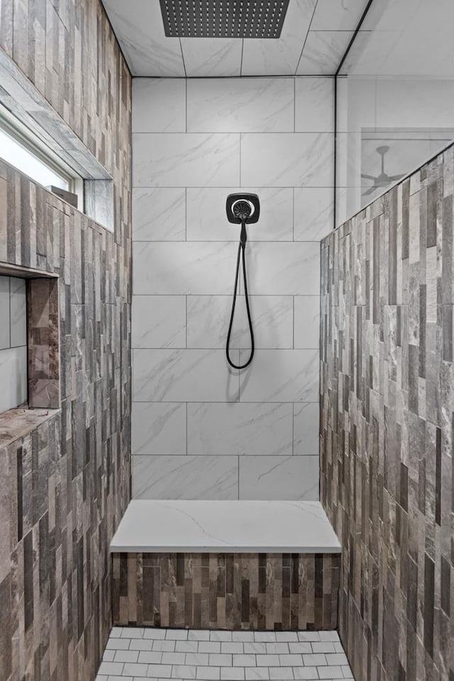 bathroom with a tile shower and tile walls