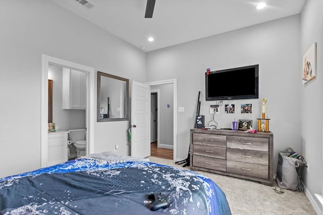 carpeted bedroom with ensuite bath and ceiling fan