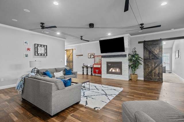 living room featuring a large fireplace, dark hardwood / wood-style floors, a barn door, and crown molding